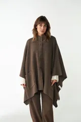 Capa color crudo de tejido de punto 100% lana fina, con cuello alto, cierre frontal con botones, bolsillos delanteros y corte asimétrico.