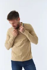 Chomba manga larga color beige con rayas horizontales blancas, cuello polo con borde azul marino y logo bordado en el pecho.