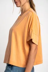 Remerón color naranja de algodón peinado con calce oversize y mangas cortas con dobladillo.