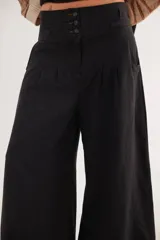 Pantalón de tiro alto en color azul, con cierre frontal de tres botones, pinzas en la cintura y corte holgado.