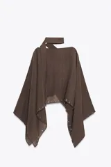 Capa marrón con cuello redondo y detalle de tachas plateadas en el ruedo. Incluye pañuelo tipo bufanda en el mismo tejido.