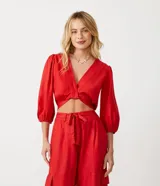 Blusa cropped roja de viscosa, con escote en V cruzado, mangas 3/4 abullonadas y lazo en la espalda.
