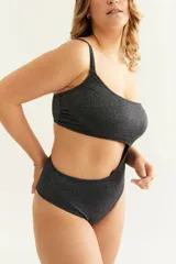 Malla enteriza negra con efecto lurex, diseño asimétrico de un solo hombro y abertura en la cintura.