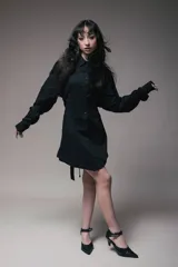 Vestido corto negro estilo camisero con botones frontales, mangas largas y lazos laterales ajustables.