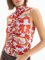 Top al cuerpo sin mangas con escote alto tipo polera y detalle de frunce en el centro delantero. Presenta un estampado full print de flores hibiscos en tonos rojos y naranjas sobre base celeste.