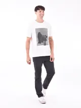 Remera de manga corta color gris topo, corte slim, con cuello redondo y un estampado gráfico en el pecho que combina texto manuscrito con un diseño abstracto en tonos oscuros.