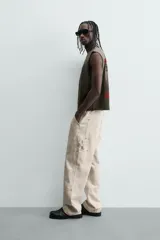 Pantalón relaxed fit color beige, confeccionado en tejido de algodón. Cuenta con bolsillos frontales, bolsillos traseros de plastrón y aplicación de bolsillos plastrón con tira multifunción en la pernera. Cierre frontal con cremallera y botón.