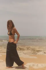 Pantalón negro de tiro medio, estilo culotte, con cintura elástica fruncida y piernas muy anchas. Posee bolsillos laterales ocultos.