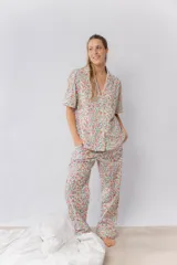 Pijama de algodón estampado "Liberty" con diseño floral multicolor. Incluye camisa de manga corta abotonada con detalles de picot en la parte delantera, mangas y bolsillo, y pantalón con dos bolsillos, elástico en la cintura y detalle de picot en los bajos.