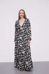 Vestido largo de poliéster con estampado floral en blanco y negro, escote en V, corte imperio con punto smock en la cintura y mangas largas con puños elásticos.