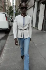 Blazer de textura suave, cuello redondo y manga larga. Presenta un diseño minimalista con cierre frontal mediante un cinturón fino de cuero con hebilla metálica.