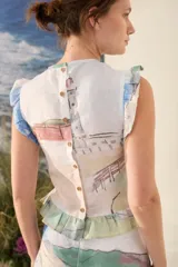 Top de lino sin mangas, con diseño fruncido en el cuerpo, cuello redondo y volados en los hombros y el ruedo. Presenta un estampado artístico en tonos celestes, verdes y rosados sobre base blanca.