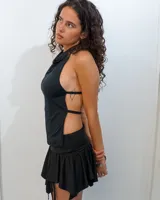 Top negro de diseño minimalista con escote halter y espalda descubierta, con tiras horizontales que se ajustan al torso.