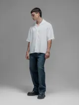 Camisa blanca de manga corta, con cuello clásico y cierre de botones frontal.