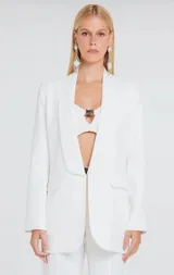 Blazer de sastrería color rosado con diseño estructurado, cuello solapa redondeado y cierre frontal con broche metálico. Cuenta con bolsillos laterales con solapa y un bolsillo superior decorativo.