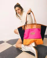 Bolso de fin de semana estilo shopper de lona y gamuza, con diseño colorblock en tonos fucsia, naranja y azul marino, asas de cuero y llavero con borla colgante.