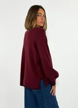 Sweater de tejido de punto en color azul marino, con cuello redondo, mangas largas con puños acanalados y ajuste holgado. Presenta un pequeño aplique decorativo en el ruedo.