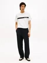 Remera de algodón blanco con cuello redondo y manga corta. Presenta una banda horizontal negra en el pecho con el nombre de la marca estampado en tipografía cursiva blanca.