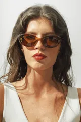 Lentes de sol con montura ovalada color marrón carey y lentes marrones.