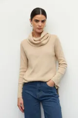 Polera de cuello alto holgado, manga larga y diseño de tejido fino con aberturas laterales en el ruedo.