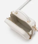 Bolso transversal tipo camera bag, color blanco con textura matelasse de rombos. Tiene correa fina ajustable y removible, cierre de cremallera y colgante de pompón.