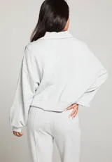 Buzo gris jaspeado de polar, con cuello en V y mangas largas.