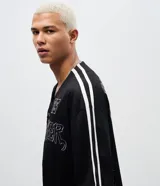 Camisa deportiva de estilo béisbol confeccionada en tejido mesh negro. Presenta cuello en V, cierre frontal con botones a presión, mangas cortas con franjas laterales blancas y bordado con la palabra Breaker y el número 96 en el frente.