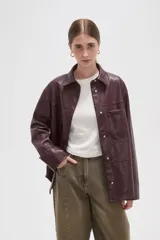 Sobrecamisa de cuero sintético en tono bordó oscuro, con cuello clásico, cierre frontal oculto y un bolsillo aplicado en el pecho. Presenta un corte holgado con mangas largas y puños rectos.