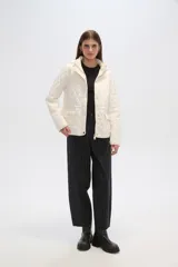 Campera acolchada de color blanco con diseño capitoneado en forma de rombos, manga larga, capucha y cierre frontal con botones a presión dorados.