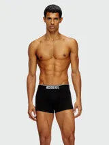 Pack de tres bóxers Diesel, uno negro con elástico blanco y logo, y dos con estampado de camuflaje en tonos grises y negros.