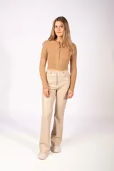 Pantalón de cuero sintético color beige, de corte recto y tiro alto, con cierre frontal y bolsillos laterales.