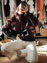 Buzo de lana uruguaya con diseño patchwork geométrico inspirado en el Tetris. Presenta una combinación de texturas y colores en tonos marrón, negro, rojo y gris, con una etiqueta de cuero en la parte inferior trasera.