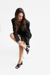 Sandalias de tacón color beige, con tiras cruzadas en el empeine y tacón geométrico negro.