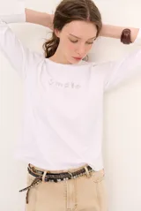 Remera blanca de manga larga con cuello redondo y diseño bordado en el pecho.