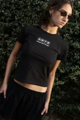 Camiseta corta negra con cuello redondo y estampado blanco con el logo de la marca "ARTE Independent Design".