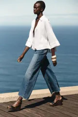 Camisa blanca de lino con cuello solapa, escote pico, manga ancha por debajo del codo con vuelta y bajo asimétrico.