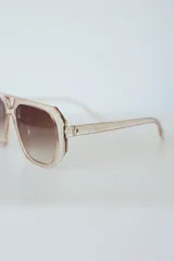 Lentes de sol con armazón de policarbonato negro y cristales tonalidad ámbar, con diseño de puente doble estilo aviador.