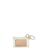 Estuche para tarjetas y llavero color marfil de cuero sintético, decorado con tachas doradas a lo largo de los bordes superiores y laterales. Incluye un sistema de argollas y gancho mosquetón metálico dorado con un dije redondo con logo grabado.