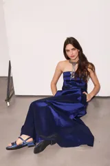 Vestido largo azul con escote strapless, corte suelto y fluido, confeccionado en tafeta con efecto tornasolado, y bolsillos ocultos en los laterales.