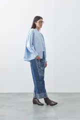 Camisa de manga larga en color celeste, con cuello mao y cierre frontal oculto. Presenta un diseño de silueta relajada con sisa caída y un bolsillo aplicado en el pecho.