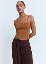 Pantalón estilo globo de color marrón, con diseño abullonado en el bajo, cintura elástica y detalle de lazos ajustables en los tobillos.