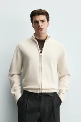 Chaqueta regular fit de punto color beige con cuello perkins, manga larga y cierre frontal con cremallera.