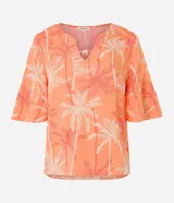 Blusa color naranja con estampado de cocoteros en blanco y rojo, cuello en V con detalle de abalorio de madera y mangas cortas acampanadas.