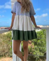 Vestido corto de corte evasé con paneles de color gris en la parte superior, blanco en el centro y verde en el ruedo. Tiene mangas cortas con volados.