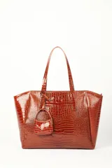 Bolso tipo shopper marrón con textura efecto cocodrilo y acabado charol, de gran tamaño y estructura semirrígida. Cuenta con doble asa de hombro y un pequeño estuche colgante desmontable.