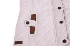 Chaleco beige capitoneado con cierre frontal y cuello de pana marrón.