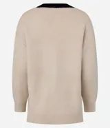 Cardigan de punto texturizado en color beige con detalles en negro en el escote en V y la vista frontal. Presenta cierre frontal con botones, mangas largas y corte holgado.