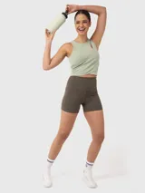Top deportivo color verde pistacho, con breteles anchos, corte crop, espalda deportiva y abertura en el hombro.