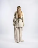Campera trench de gabardina en color beige, con solapa cruzada, doble botonadura frontal, hombreras y cinturón ajustable para anudar en la cintura. Presenta bolsillos delanteros y puños ajustables con tiras.