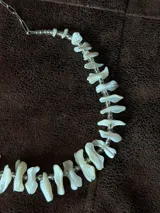 Gargantilla corta compuesta por bastones irregulares de nácar natural en tono blanco y cuentas transparentes intercaladas.